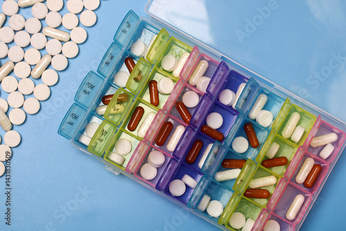 Daily pill organizer box containing variety of colorful medicine and vitamins. pillbox