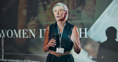 Business, speech and woman at seminar on stage for motivation at tech conference. Convention, talk and keynote speaker at event for training, coaching and inspiration with mature developer with mic
