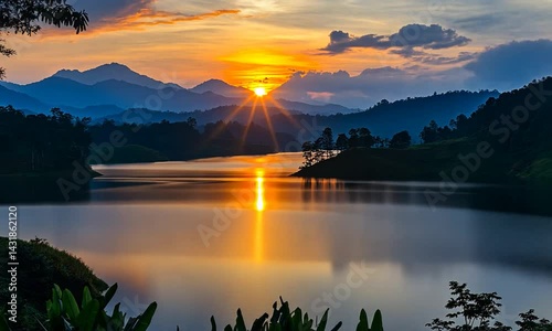 Serene sunset over a tranquil lake surrounded by mountains and lush greenery