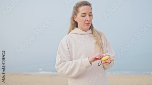 girl wear wireless earbuds and listening music on a beach. Attractive joyful woman on a beach