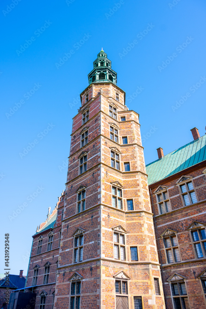 A towering structure of Rosenborg Castle stands against a bright blue sky in Copenhagen, Denmark. The intricate brickwork and green roof highlight the castle's historic architecture. A towering structure of Rosenborg Castle stands against a bright blue sky in Copenhagen, Denmark. The intricate brickwork and green roof highlight the castle's historic architecture.