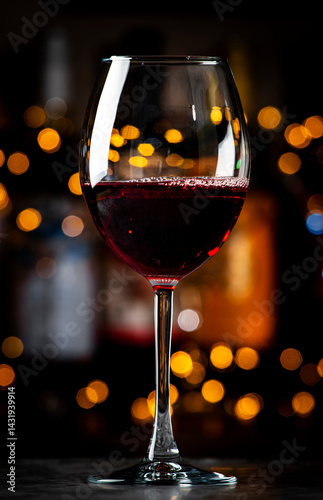 Italian dry red wine sangiovese in glass and wine bottles on dark bar background with lights