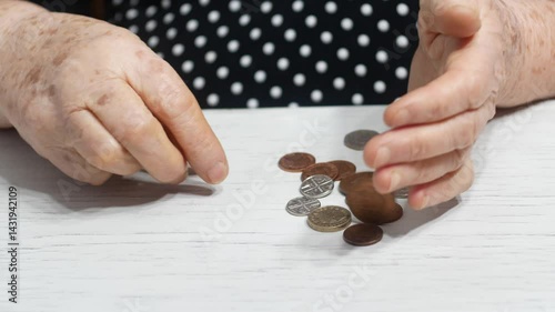  An elderly person`s hands pour out British coins onto a table and begin to count them.