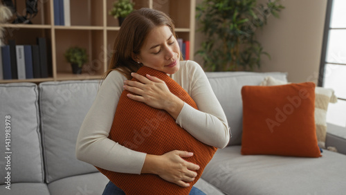 Woman relaxing indoors on sofa hugging pillow in cozy living room with neutral tones showing calm and peaceful atmosphere in home interior setting