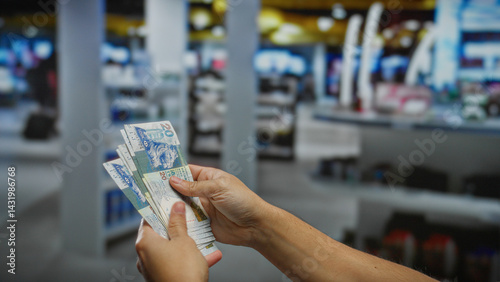 Man holding hong kong dollars in airport terminal showcasing international travel finance and investment.