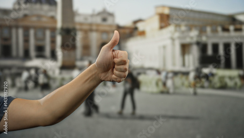 Obraz na płótnie Man giving thumbs up with arm extended in front of st. peter's square, vatican, showing positive gesture in iconic outdoor location. w salonie