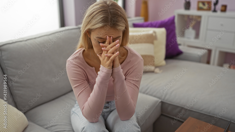 Woman sitting on a couch in a living room with her head in her hands depicting stress or contemplation, featuring modern home decor and a cozy atmosphere.