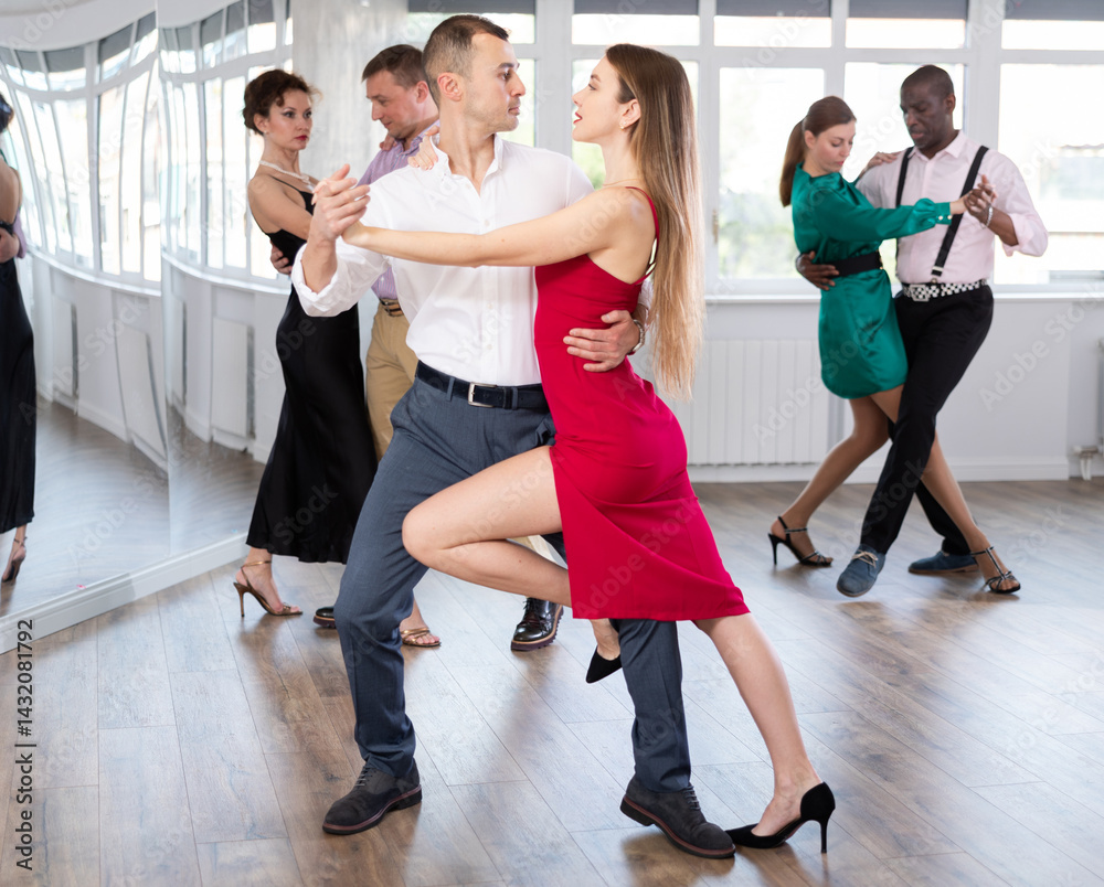 Fototapeta premium Active young lady training waltz in pair with man in dance-hall during dancing classes