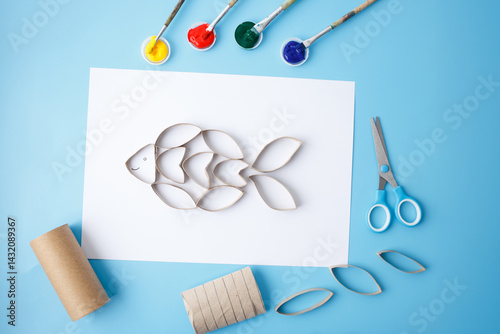 flat lay of funny fish craft made from recycled toilet paper roll. sustainable craft idea for small motor skills development, early childhood education, art classes,