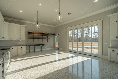 Interior kitchen featuring white cabinets and a terrazzo floor natural light shining through a glass door and a view to the outside.