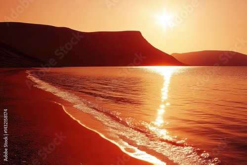 Golden sunset over a tranquil beach.  A fiery orange sunrise paints the sky and sea, with waves gently lapping at the shore.  Silhouette mountains rise in the distance
