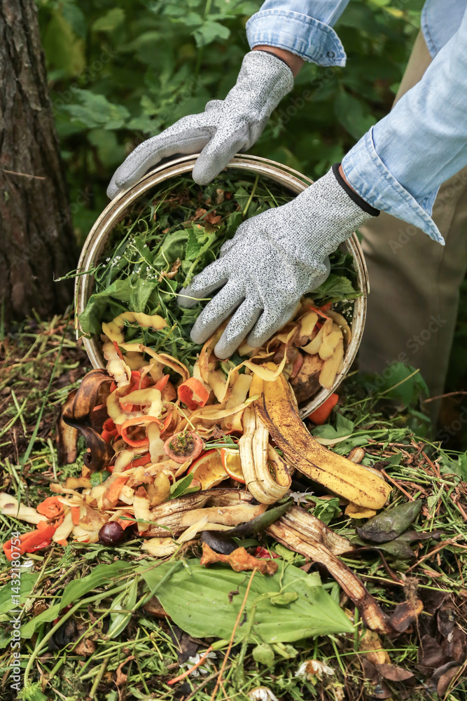 Obraz premium Compost heap pile with bio waste close up. Farmer with vegetables and fruits food scraps and grass in bucket for compost. Zero waste, composting concept