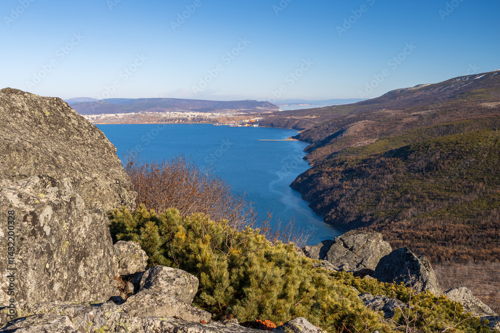 View from the mountain to the bay and the coast. Rocks in the foreground. Port city in the distance. Surroundings of the city of Magadan, Magadan region, Far East of Russia. Nagaev Bay, Sea of Okhotsk
