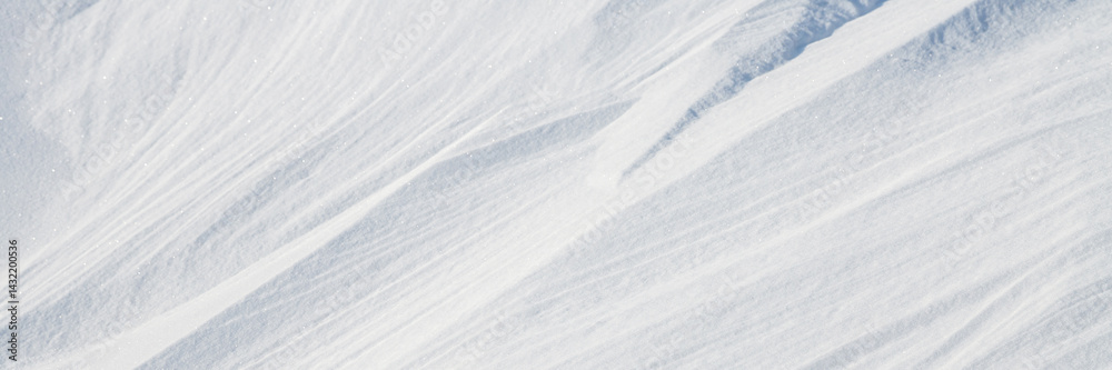 Beautiful winter background with snowy ground. Natural snow texture. Wind sculpted patterns on snow surface. Wide panoramic texture for background and design.