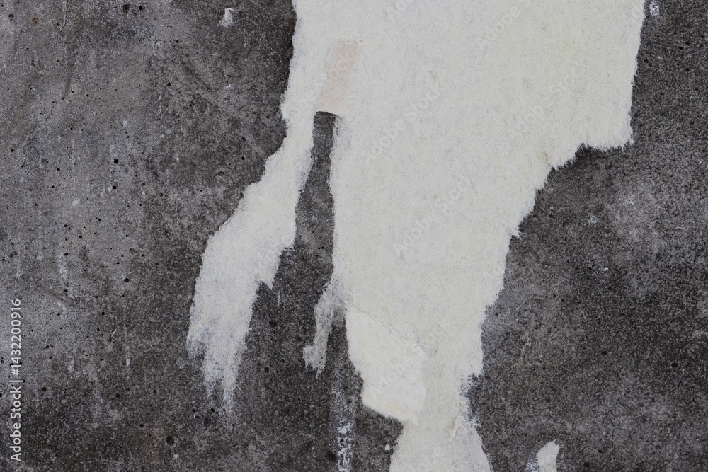 Torn old faded paper wallpaper on a concrete wall. Ragged scraps of white paper on a gray background. Vintage texture for background and design. Closeup view with copy space for text. High resolution.