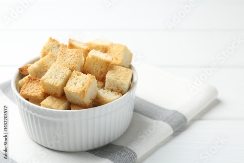 Delicious crispy croutons on white table, closeup. Space for text