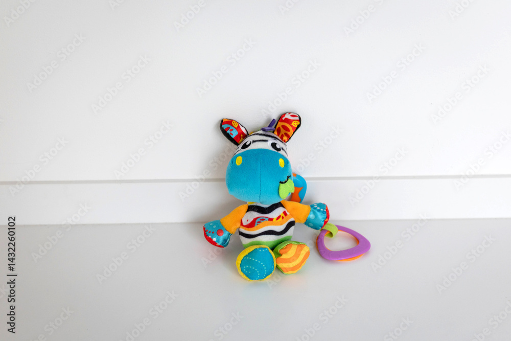 Naklejka premium Colorful Stuffed Animal Toy Holding a Ring with Patterned Ears and Multicolored Body