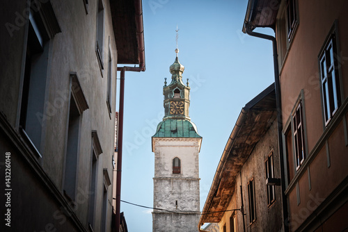 Copper‑topped clock tower of the Church of Saint Jacob (cerkev svetega jakoba) between medieval houses in skofja Loka, Slovenia, catching afternoon light and illustrating catholic religious heritage. photo