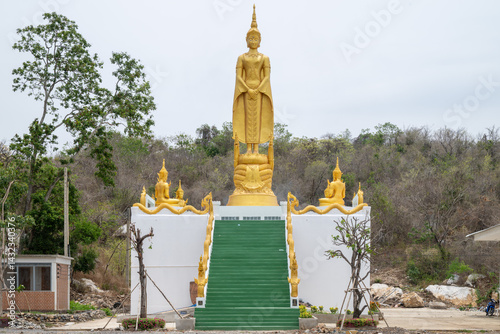 Lopburi, Thailand, April 14, 2025, Majestic yellow Buddha statue at Wat Tamtako amidst lush greenery