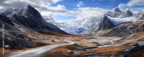 Scenic mountain valley road trip winds through rugged terrain with snow-capped peaks on cloudy day