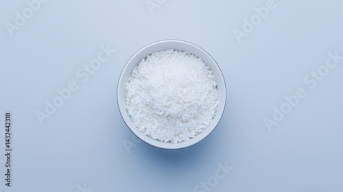 A bowl filled with white rice, set against a minimalist blue background, showcasing the simplicity and purity of the grain.