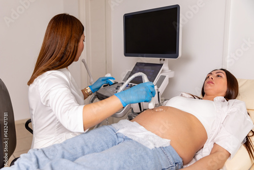 Obraz na płótnie Happy pregnancy time, ultrasound concept. Pretty pregnant woman doing ultrasound scan in the prenatal clinic, worried about health of her future baby. Female doctor looking at the screen w salonie