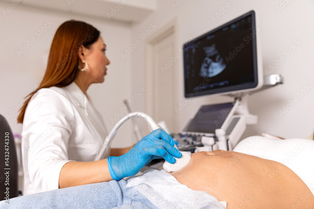 Happy pregnancy time, ultrasound concept. Pretty pregnant woman doing ultrasound scan in prenatal clinic. Professional female doctor screening of pregnant woman by ultrasound, looking at the screen