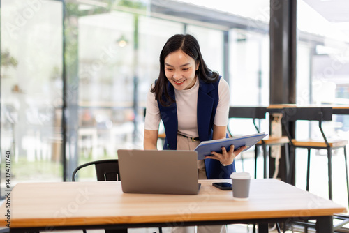 Wallpaper Mural asian business woman sit at laptop holding papers, read received contract, agreement, legal documents smile feel satisfied, got good news. Loan repayment, career advance, success concept
 Torontodigital.ca