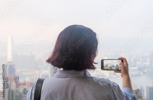 Photography Young woman takes video on a phone at famous beautiful place in Hong Kong, Victoria Peak, rear view
