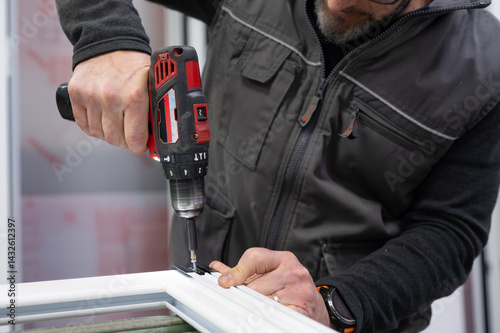 Carpenter using cordless drill assembling aluminum window frame