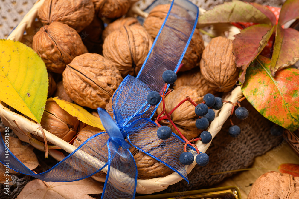 nuts in a basket with autumn leaves and a blue bow on a wooden background close-up as a background or decoration