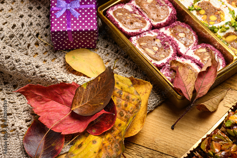 Sweet food Turkish delight on wooden background with autumn leaves, assorted locum and candy for decorated backdrop