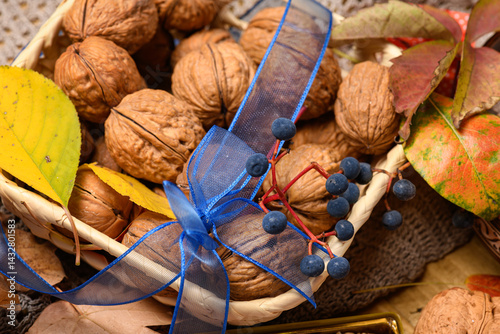 Obraz na płótnie nuts in a basket with autumn leaves and a blue bow on a wooden background close-up as a background or decoration w salonie