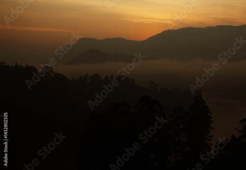 Golden mist blankets mountain silhouettes.