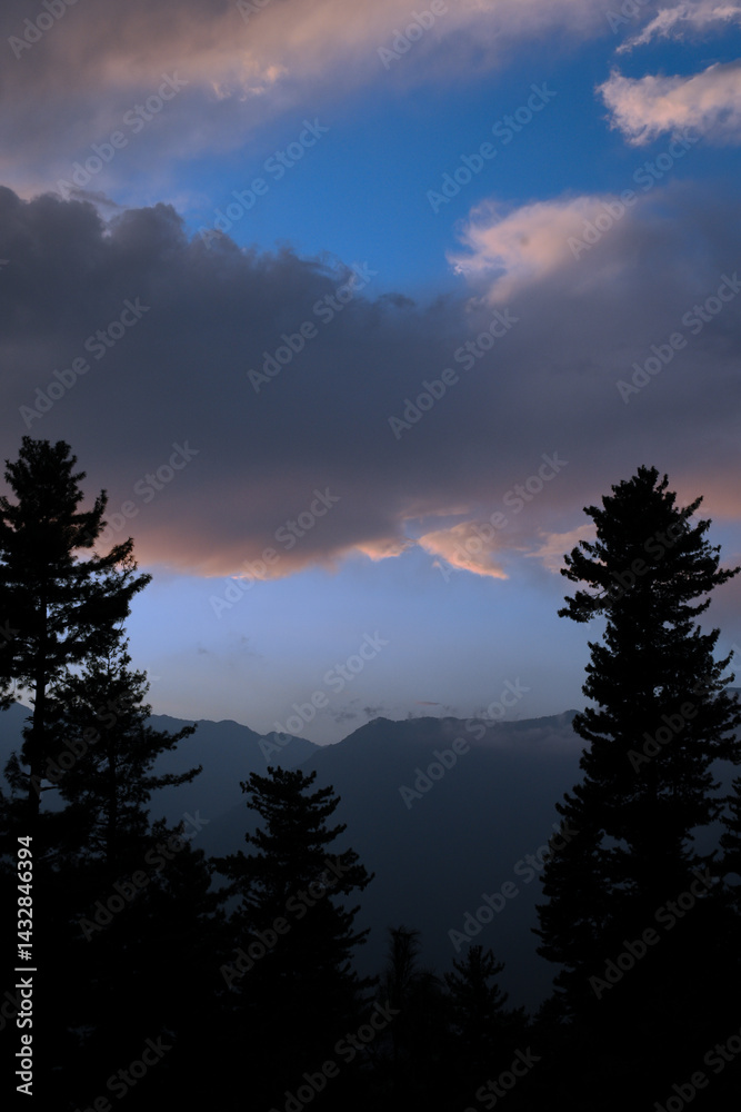 Vertical picture of pastel pink color sky and mountains and cedar trees taken during magical hour in evening. Vertical picture of pastel pink color sky and mountains and cedar trees taken during magical hour in evening.