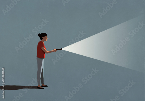 Woman holding bright flashlight in darkness
