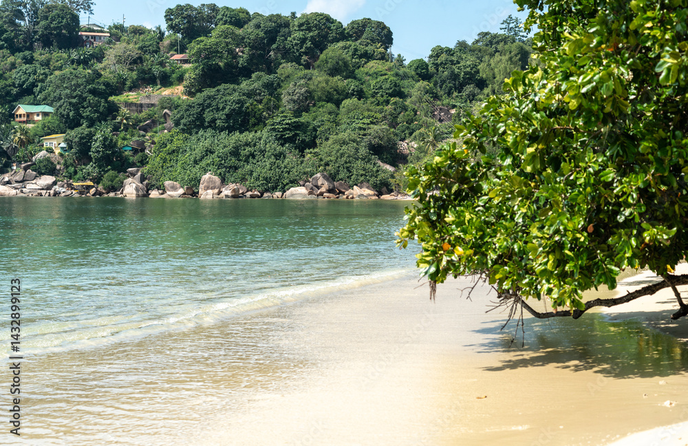 Coastal view of Anse Marie Louise in Seychelles with sandy beach, calm water, green hills