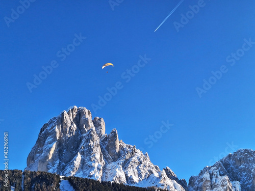 View of a flying parachutist and an airplane with a condensation trail.