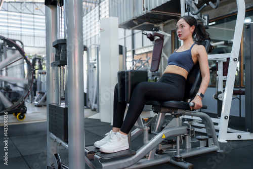 Fotografi Young sportswoman exercising inner thigh muscles on a fitness machine in a moder