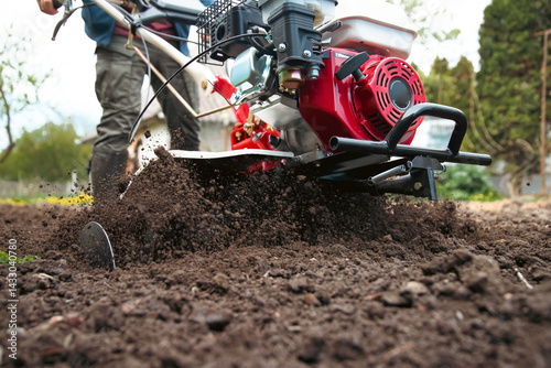 Fotografie Farmer using tiller on a plowed field