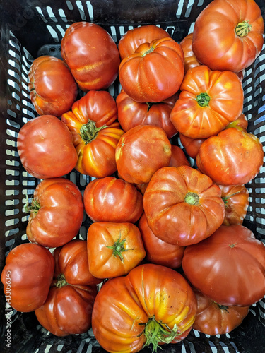 A full basket of vibrant heirloom tomatoes, showcasing a variety of shapes and sizes ready to eat.