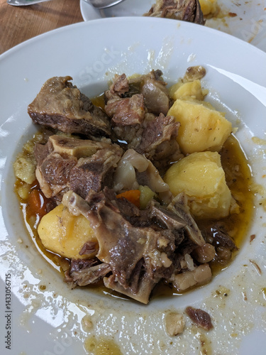 A close-up shot reveals a plate filled with a flavorful beef stew, potatoes and vegetables.