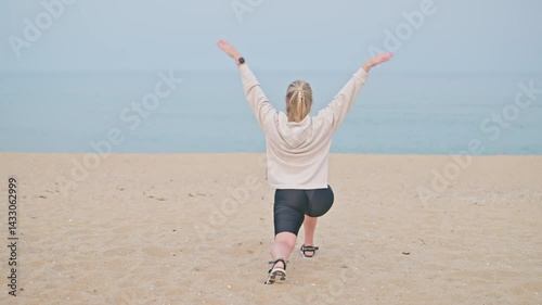 Behind view young woman stretching legs and body runner on the beach. Wellness, warm up