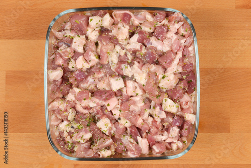 Obraz na płótnie Diced and seasoned pork meat, prepared with spices for sausage making, fills a square glass dish on a wooden surface w salonie