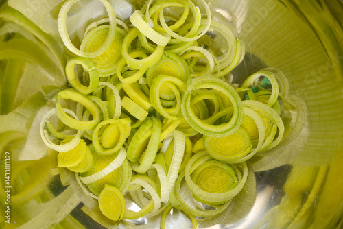 Obraz na płótnie Sliced light green and white leeks fill a metallic bowl, showcasing their circular rings and layers w salonie