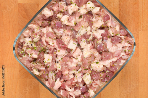 Obraz na płótnie Diced and seasoned pork meat, prepared with spices for sausage making, fills a square glass dish on a wooden surface w salonie