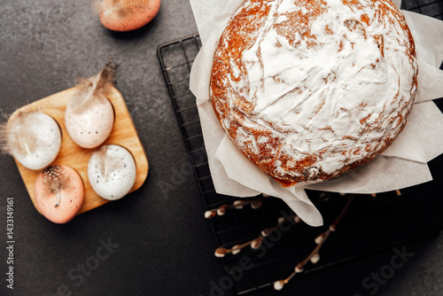 Closeup of Easter cake and pastel eggs with soft feathers. Dark background holiday concept.