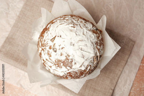 Traditional Easter cake with powdered sugar on soft beige linen background. Rustic homemade dessert for spring holiday