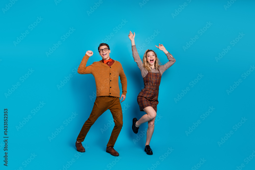 Playful young couple dressed stylishly on blue background showcasing retro vibes