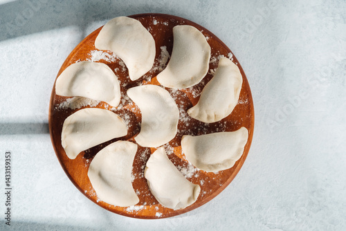 Obraz na płótnie Dumplings freshly prepared on a wooden plate with flour scattered around w salonie